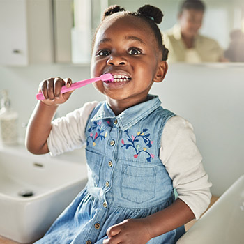 small girl with pigtails brushing her teeth