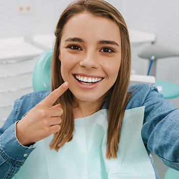 women with white teeth smiling whilst talking on the phone